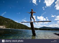a-young-man-balances-on-a-teeter-totters-high-above-a-lake-in-idaho-X60K40.jpg